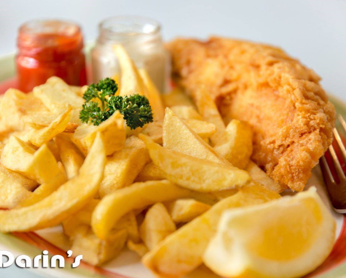 Golden fish and chips from Darin's in Edinburgh served with sauces and parsley.